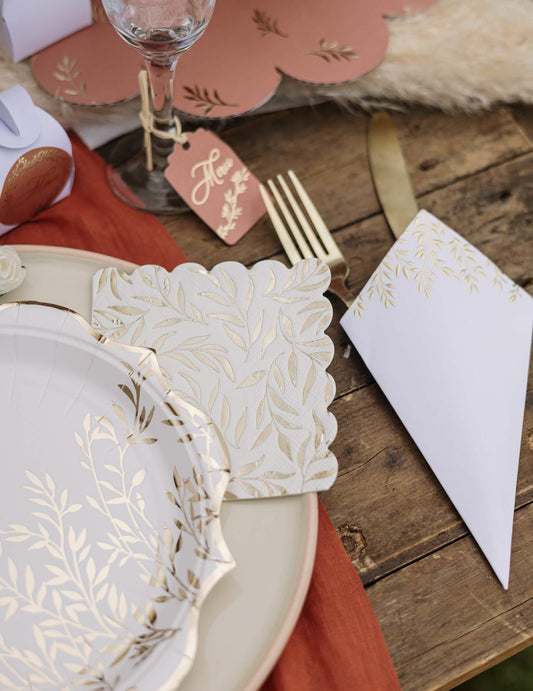 Mise en situation de table des serviettes cocktail en papier à motif feuillage festonné blanc et or