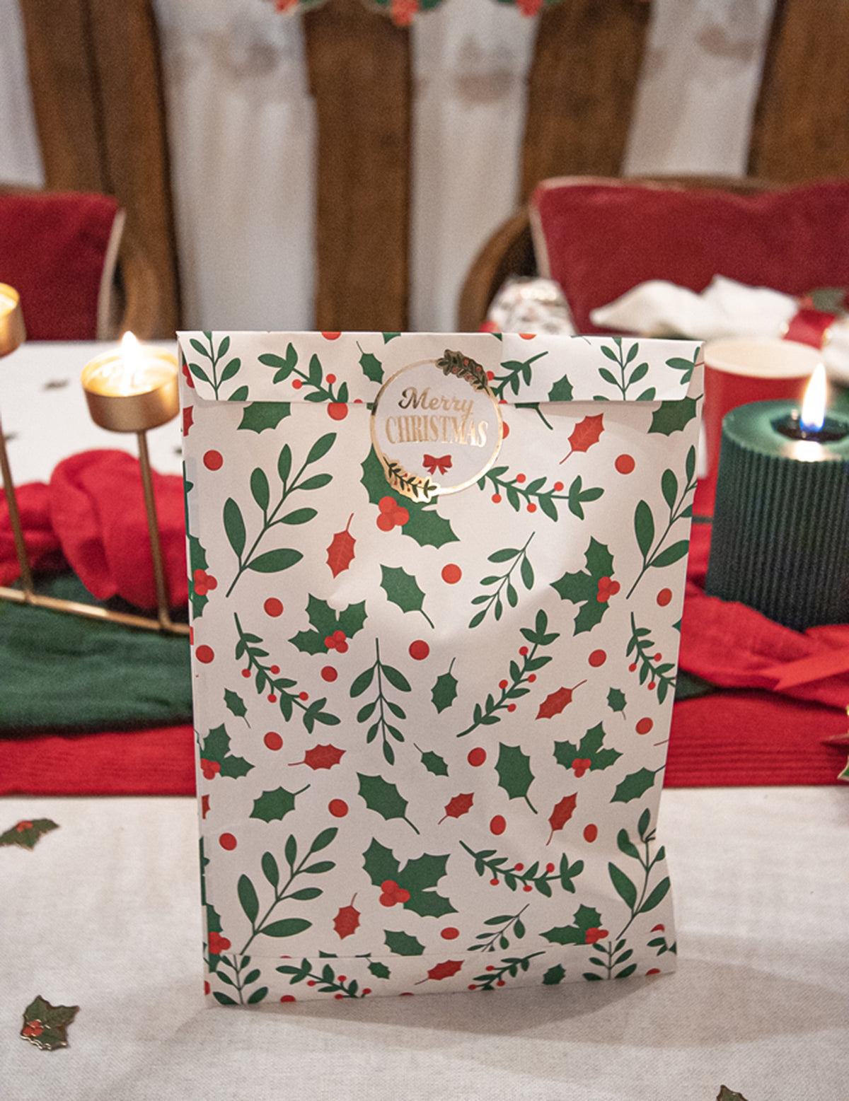 Vue de face de la pochette cadeau houx de Noël en papier fermée par un sticker doré