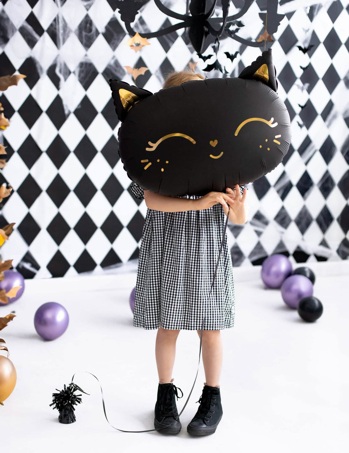 dieťa držiace pred tvárou héliový balón mačky pre halloween