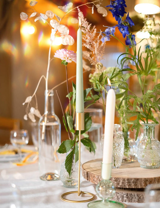 Mise en situation dans un décor floral du bougeoir design sur pied pour table métal doré