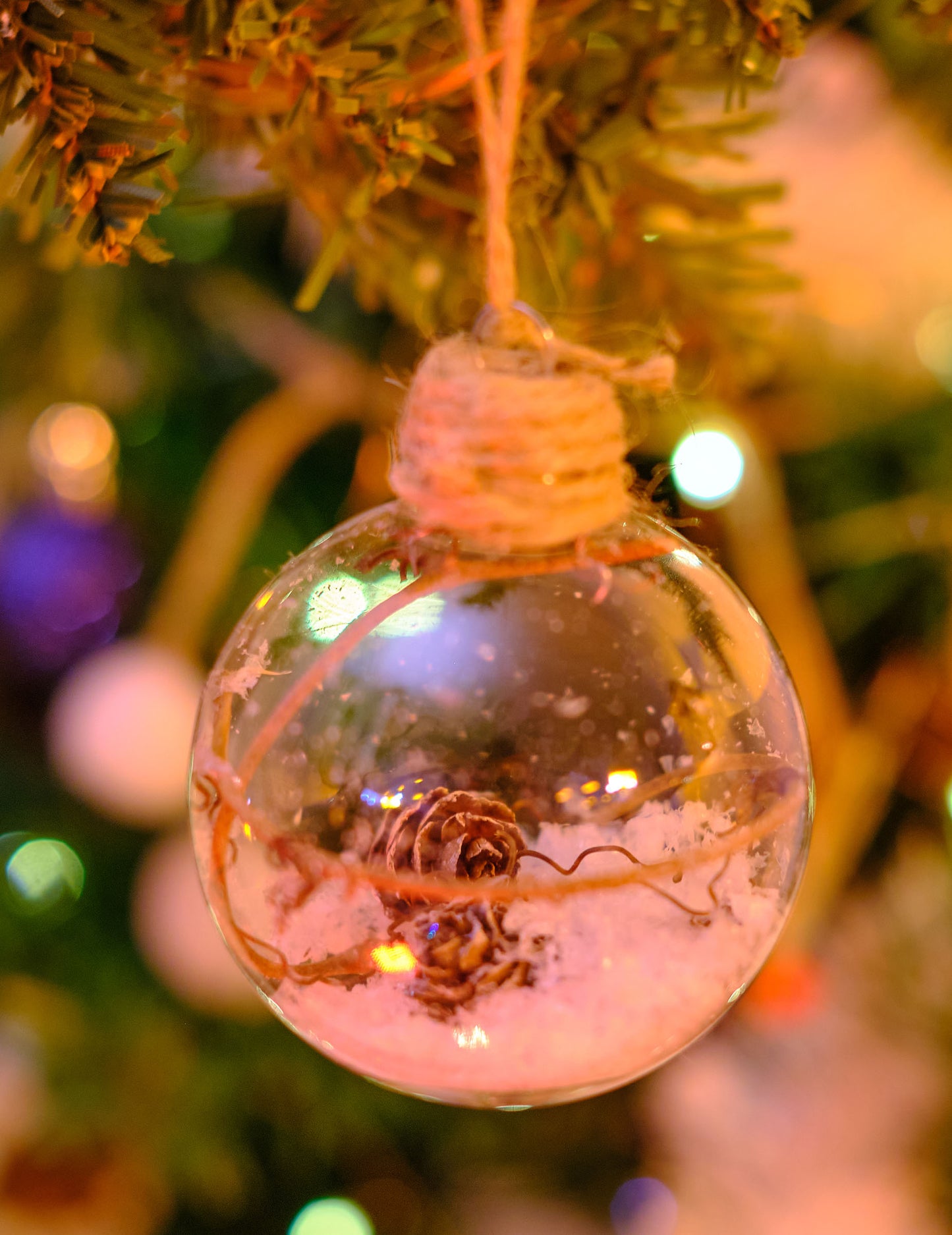 Mise en situation dans un sapin de la boule de Noël en verre avec pommes de pin et neige