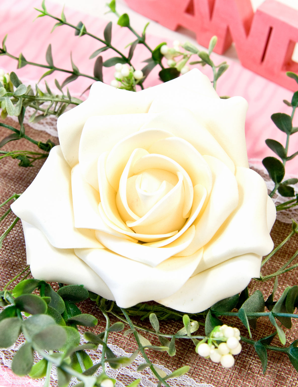 Gros plan sur la rose du centre de table rose et feuillage pour mariage champêtre