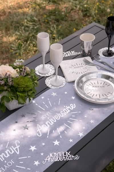 Mise en situation du chemin de table intissé anniversaire pour fête blanc et argent avec étoiles