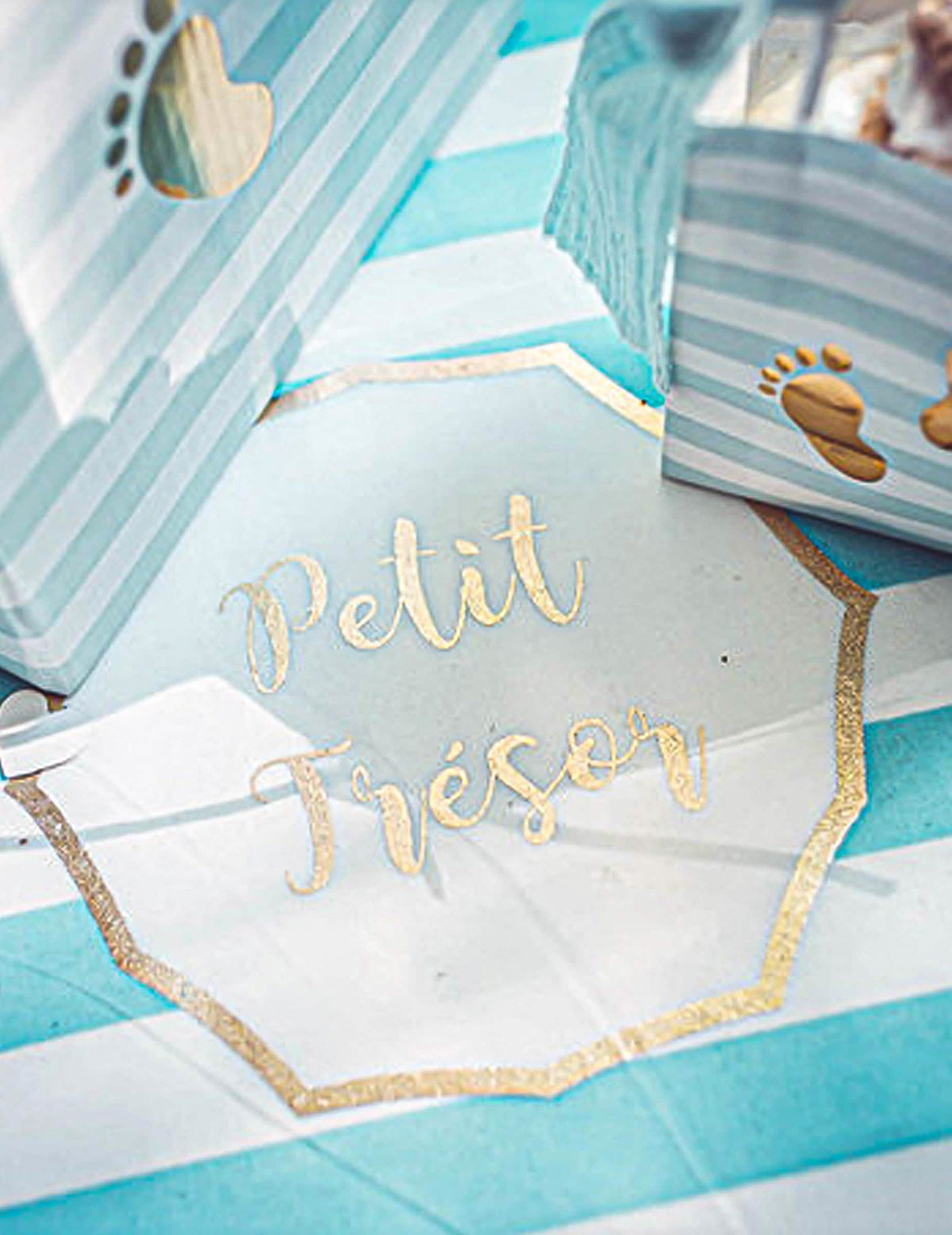 Detailný záber na zlatý nápis na behúni na stôl Petit Trésor