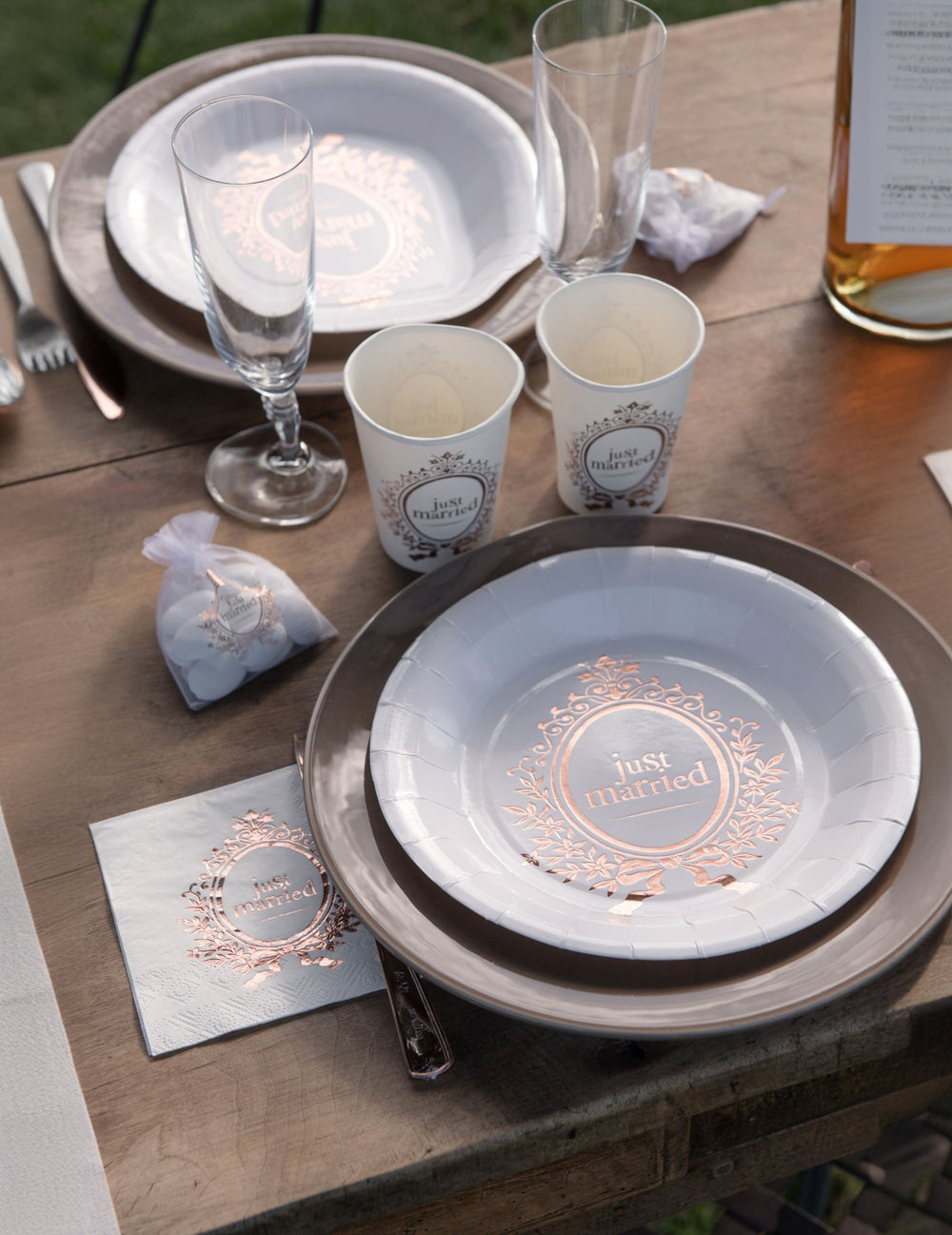 Mise en situation sur une table des assiettes en carton Just Married pour mariage chic blanches et rose gold