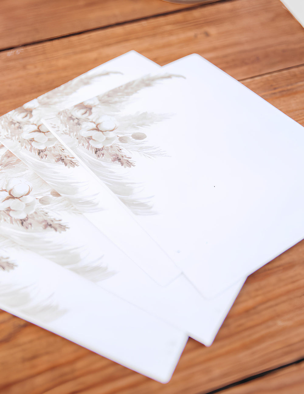 Vue en biais des invitations avec enveloppes pampas et fleurs de coton