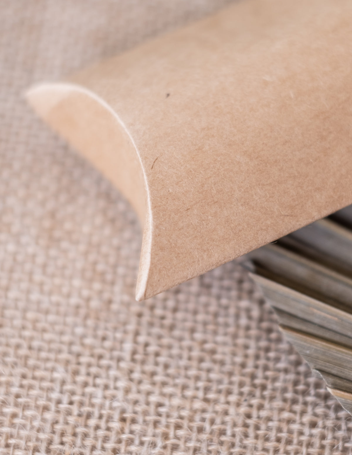 Détail de la fermeture incurvée des petites boîtes kraft pour fête marron clair en forme de berlingot