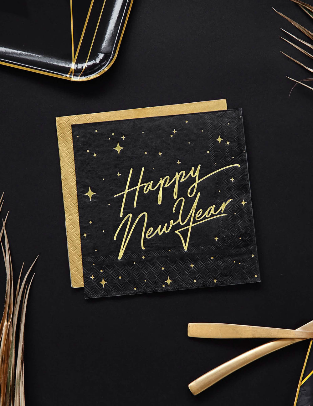 Pohľad zhora na papierové obrúsky Happy New Year čierne a zlaté so zdobením hviezdami