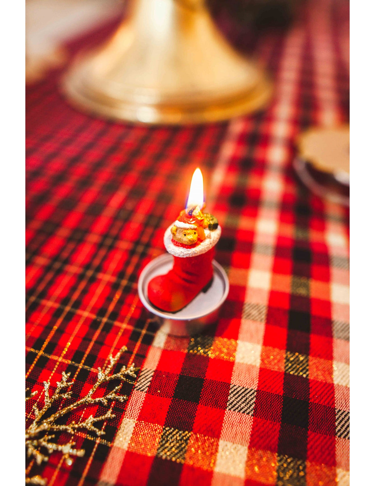 Zoom sur la bougie allumée des 3 bougies botte du père noël avec ourson