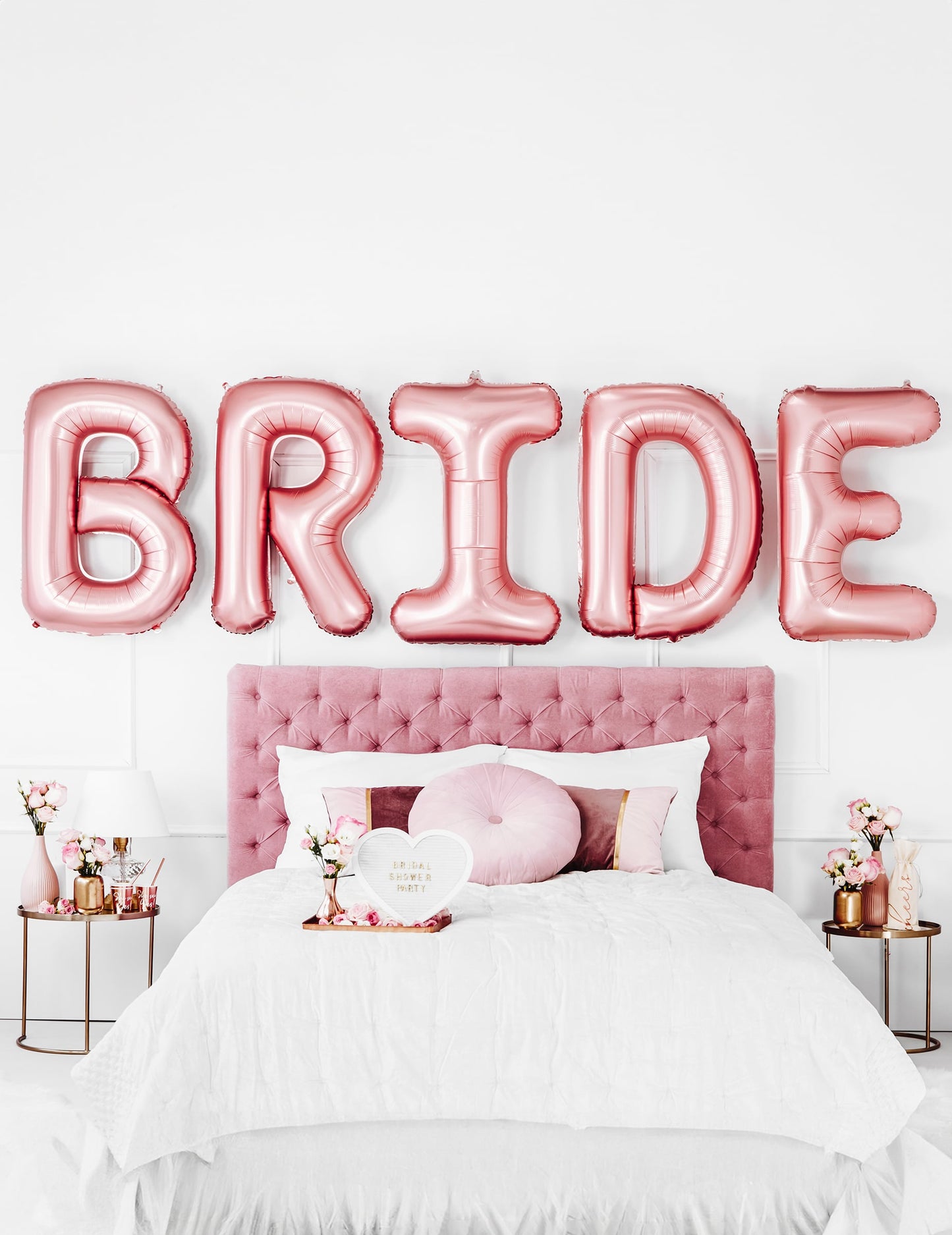 Mise en scène au-dessus d'un lit des ballons lettres Bride pour EVJF rose gold