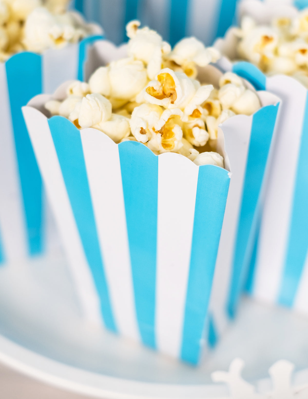 Gros plan sur l'ouverture des boîtes à popcorn à rayures pour fête bleu et blanc turquoise