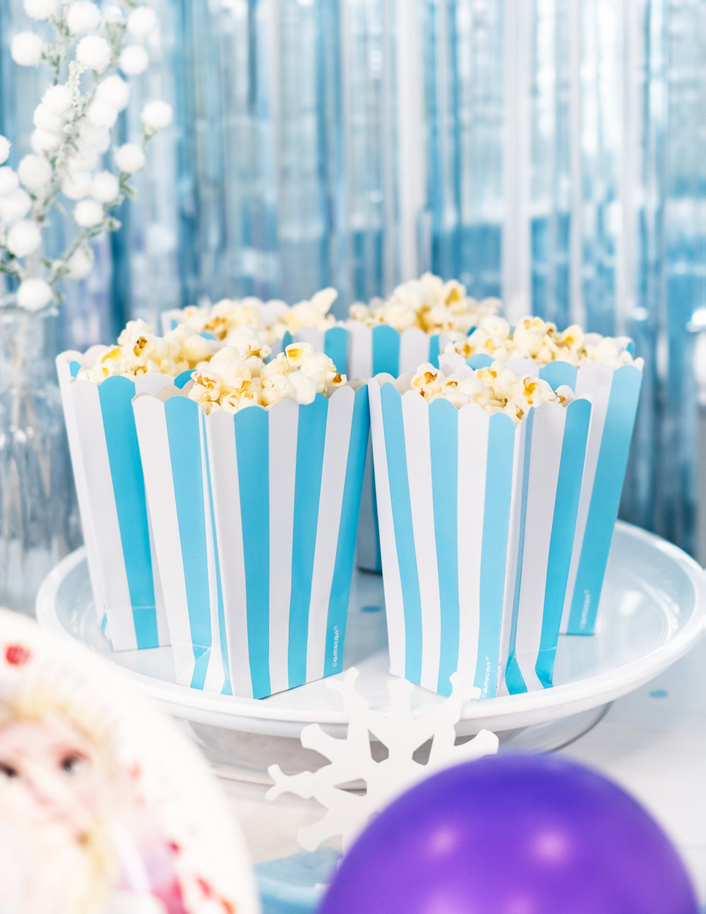 Mise en situation festive sur un plateau des boîtes à popcorn à rayures pour fête bleu et blanc turquoise