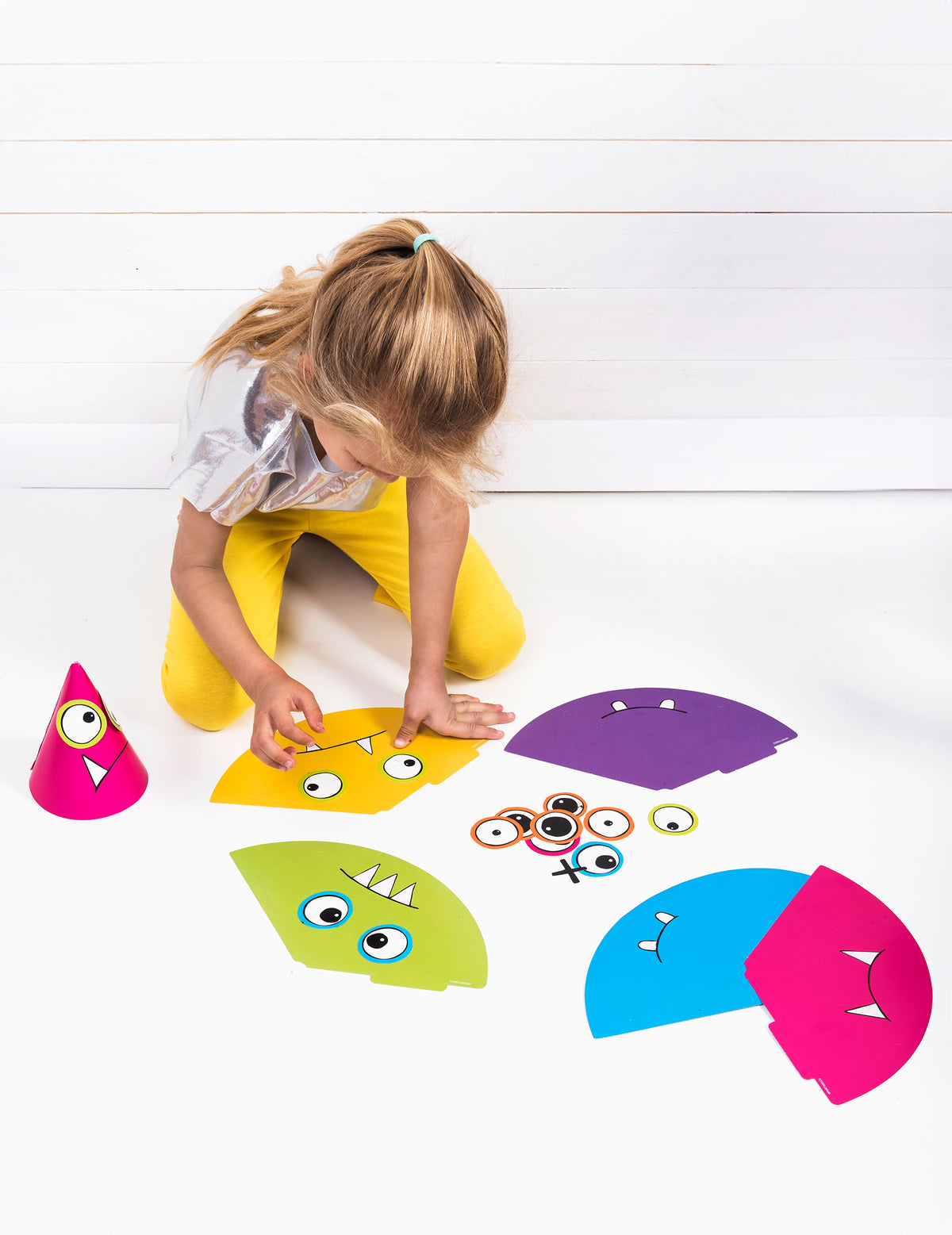Enfant assemblant les éléments du chapeaux de fête petits monstres