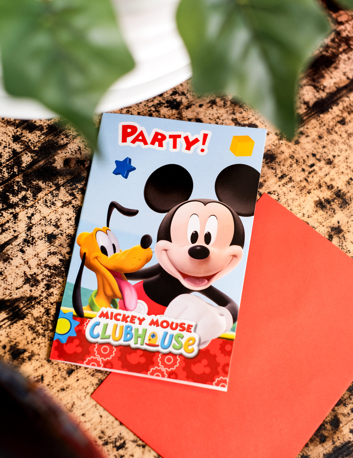 Mise en situation de l'invitation et de l'enveloppe rouge des invitations carton Mickey Mouse