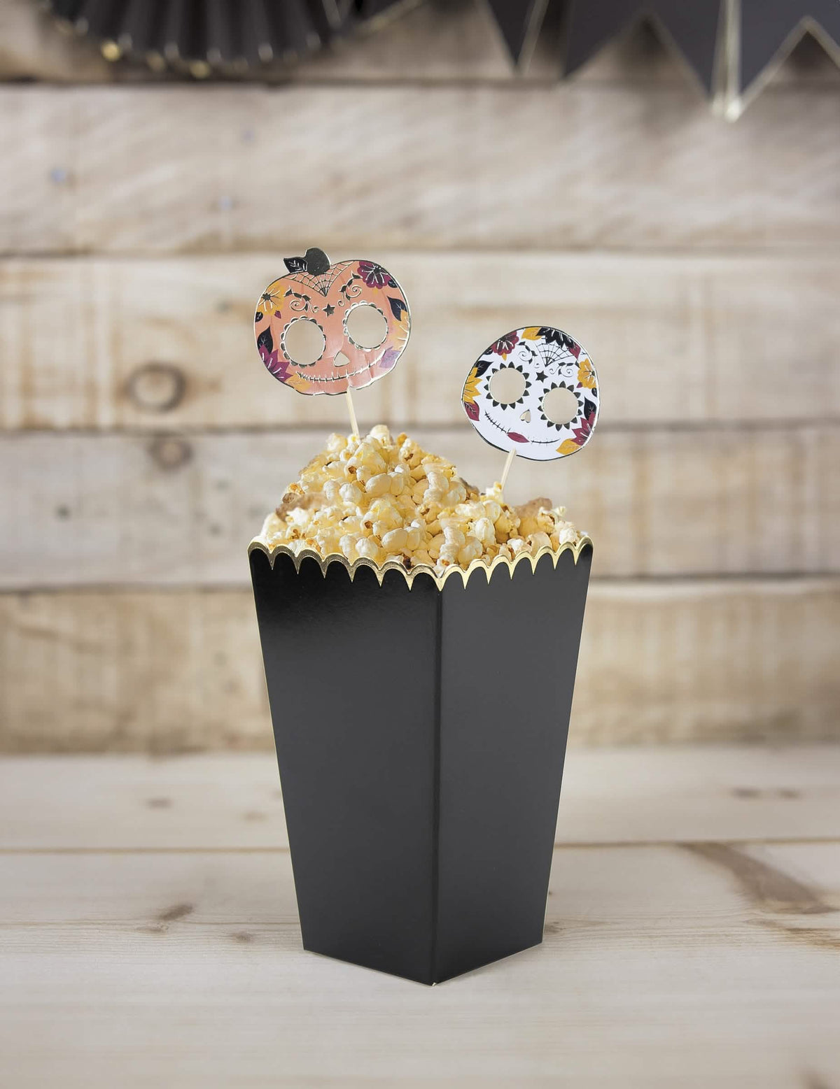 Zátišie s vroubkovanými škatuľkami na popcorn pre čiernu a zlatú párty