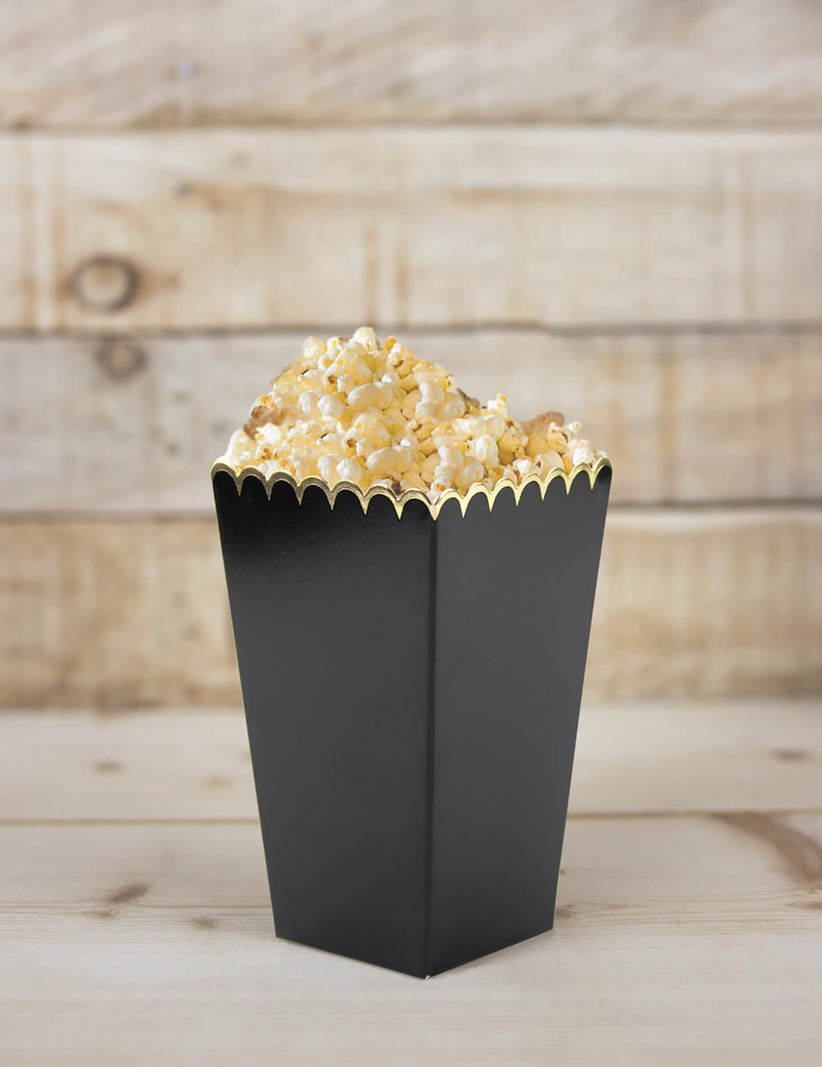 Detailný záber na škatuľu plnú čiernych a zlatá strapcových krabičiek na popcorn na oslavu