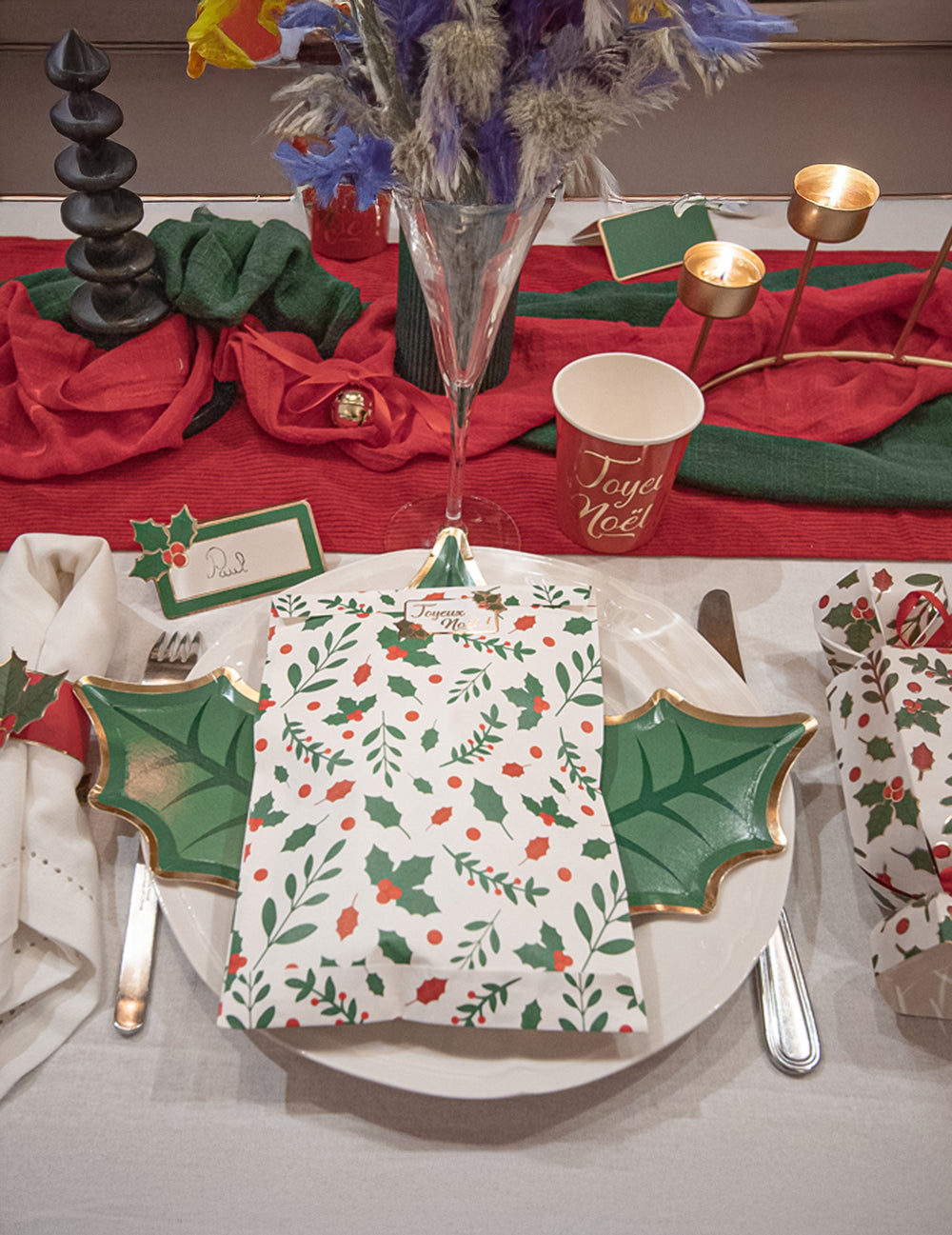 Vue de dessus d'un couvert dressé avec la pochette cadeau houx de Noël en papier