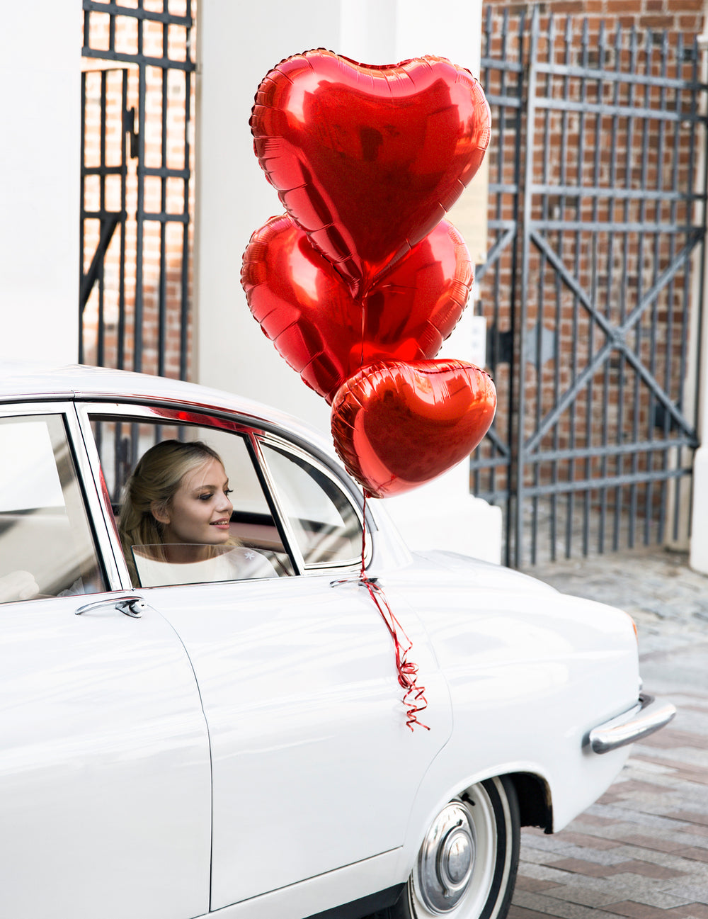 Mise en situation sur une voiture du ballon aluminium coeur pour fête rouge métallisé