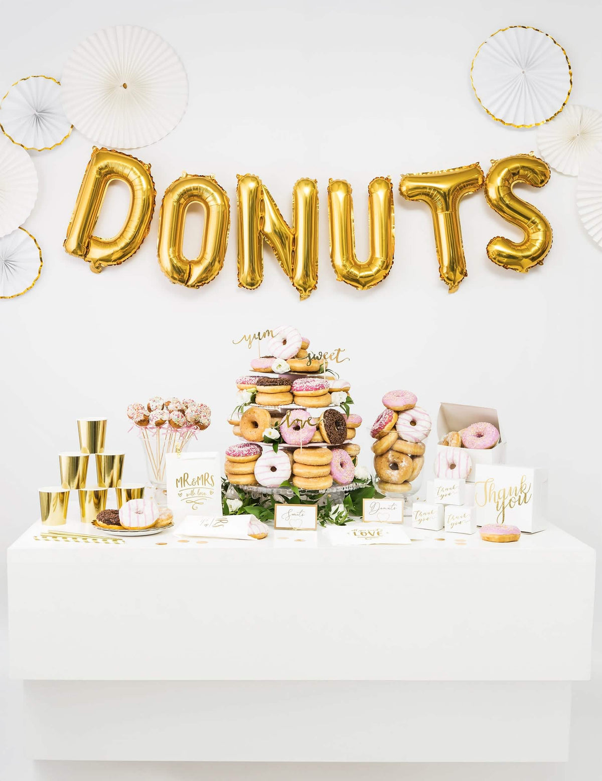 Dekorácia candy baru s nápisom DONUTS zloženým z balónov zlatej hliníkovej písmenovej fólie
