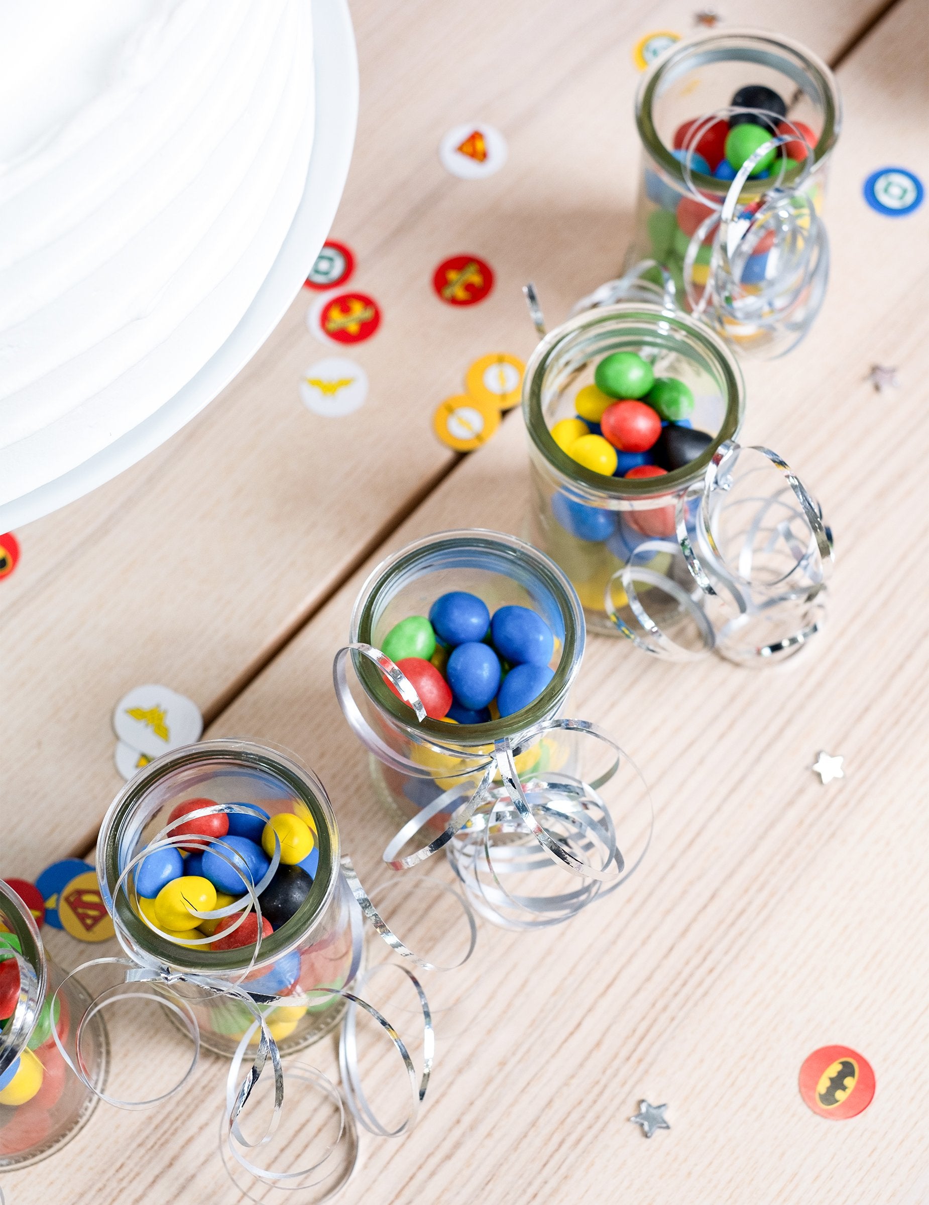 Pohľad zhora na malé poháre s cukríkmi ozdobené lesklým stužkovým pásom na dekoráciu oslavy strieborný