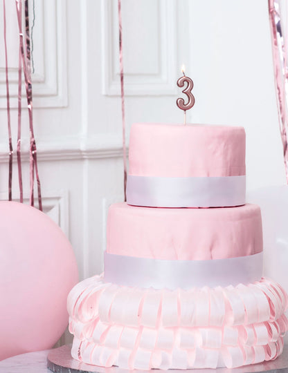 Mise en situation sur un gâteau de la bougie d'anniversaire chiffre 3 rose gold métallisée avec pic