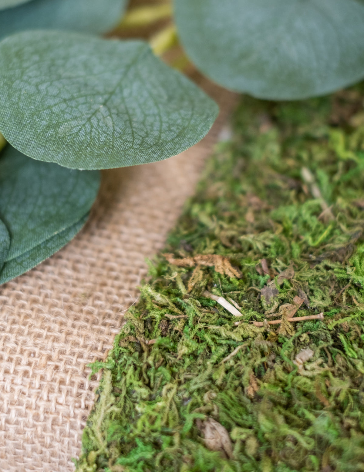 Gros plan sur la mousse et la toile de jute du chemin de table végétal en mousse naturelle pour mariage