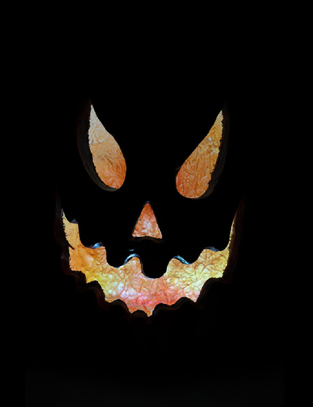Gros plan sur le regard et la bouche découpés de la citrouille lumineuse effrayante pour Halloween