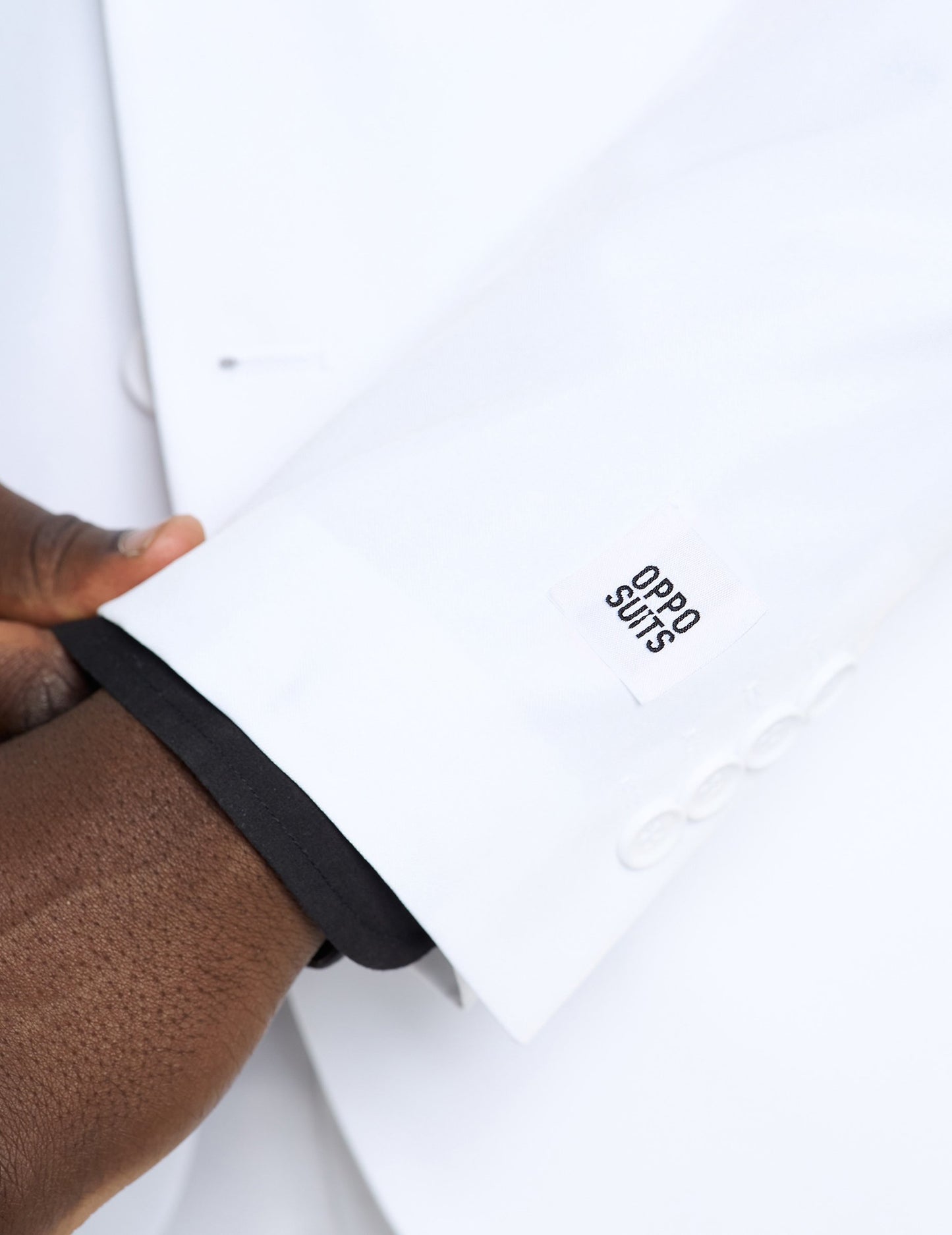 Détail de l'étiquette de marque sur la manche du Costume Mr. Blanc Opposuits