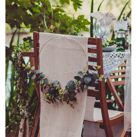Mise en situation sur un dossier de chaise de la couronne en métal d'eucalyptus et fleurs blanches cercle or