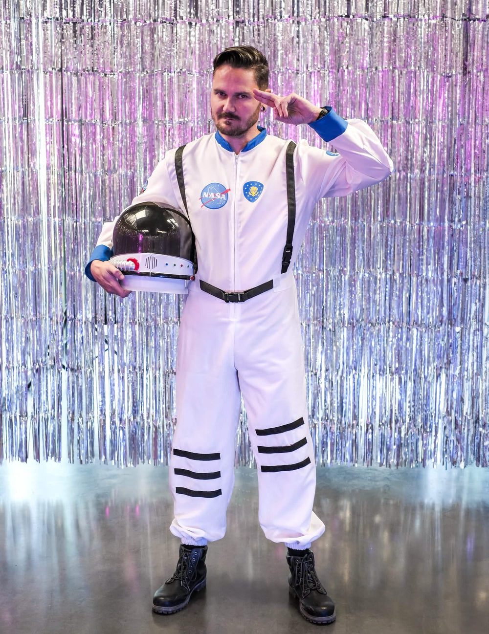 Pozícia pozdravu s prilbou pod pažou pred strieborná pozadím kostýmu astronauti z vesmíru
