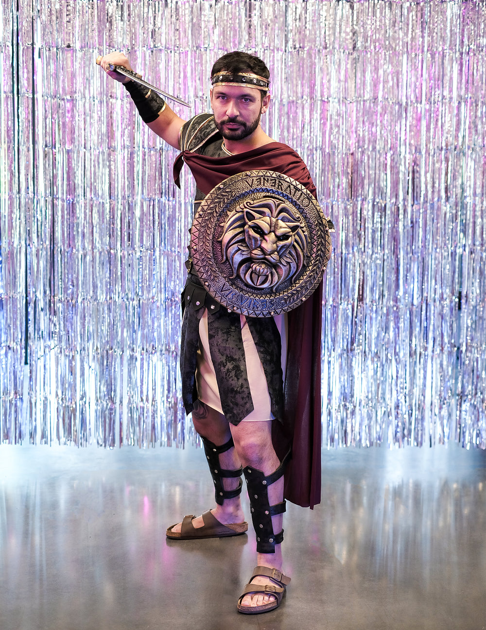 Mise en situation avec bouclier à tête de lion et épée du déguisement de gladiateur romain pour homme