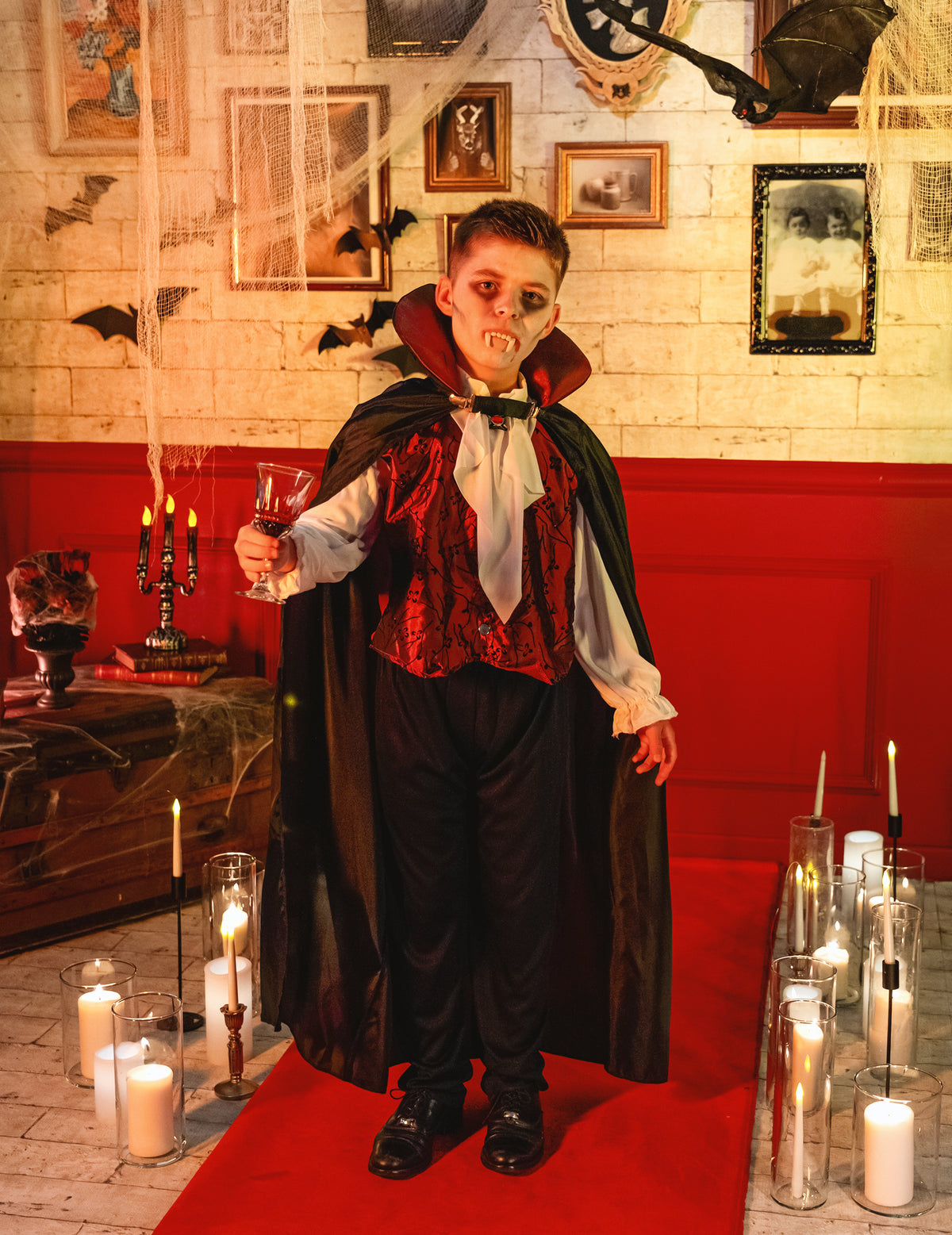 Mise en situation du déguisement vampire élégant pour garçon dans un décor d'Halloween avec bougies