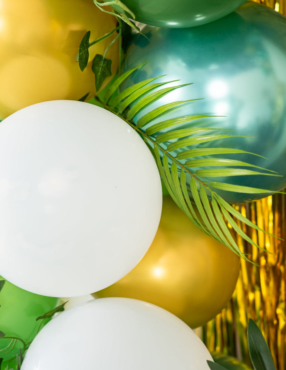 Gros plan sur les ballons et les feuilles de palmier du kit arche de 86 ballons tropicale