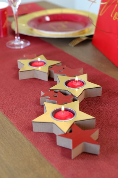 Mise en situation sur table du porte bougie étoiles pour décoration de Noël rouge et or en bois et métal
