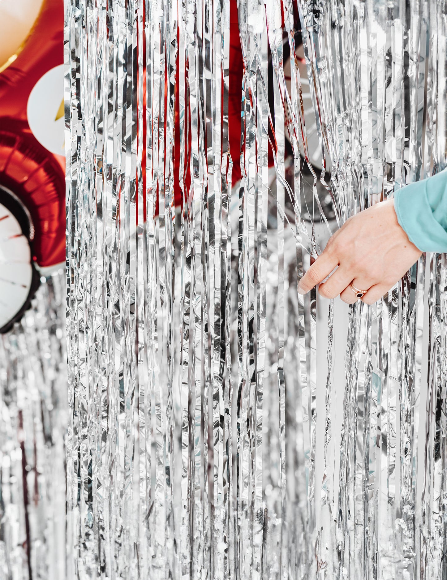 Ruka odhaľujúca strapce trblietavej opany na striebornú oslavu