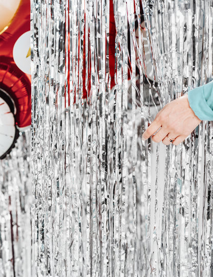 Ruka odhaľujúca strapce trblietavej opany na striebornú oslavu