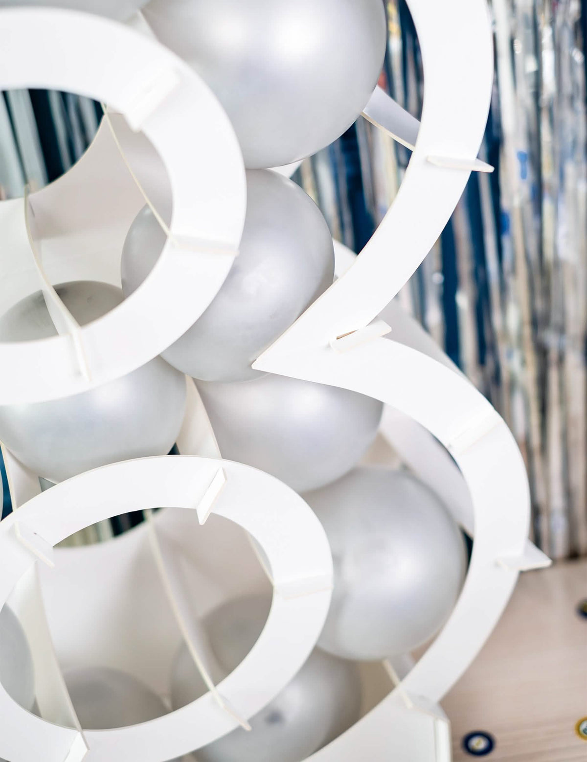 Zoom sur le garnissage de ballons de la structure chiffre pour décoration de fête blanc en carton à garnir